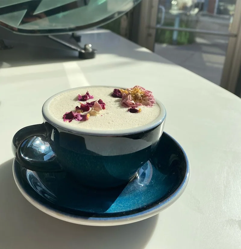 Specialty drink in a blue cup and saucer near a window at Press Cafe