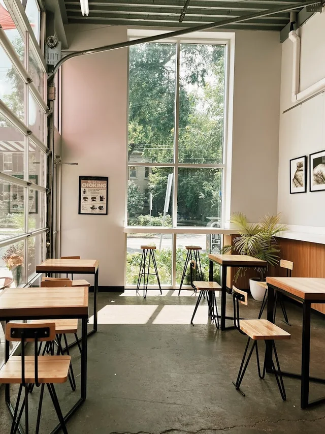 Sunlit seating area with tall windows inside Press Cafe